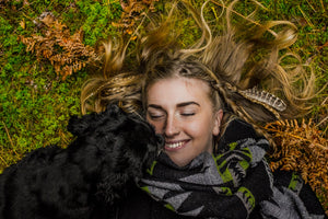 dog cuddling with human on grass
