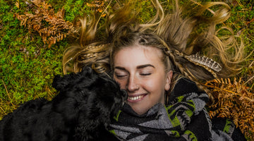 dog cuddling with human on grass