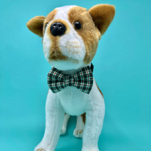 Stuffed dog toy with a plaid bow tie on a light blue background