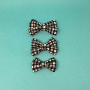 Three red and green plaid bow ties on a teal background